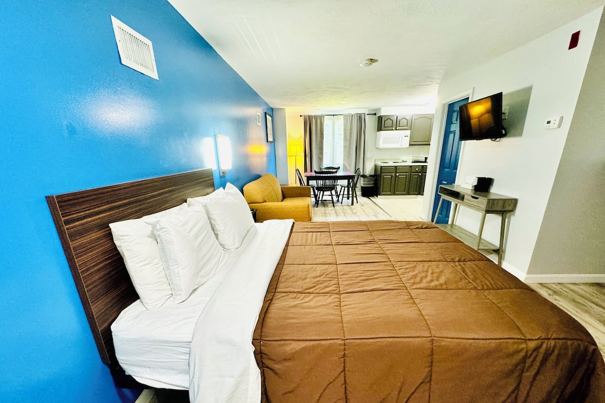 Ein Hotelzimmer mit Bett, Sofa, Essbereich und Fernseher.