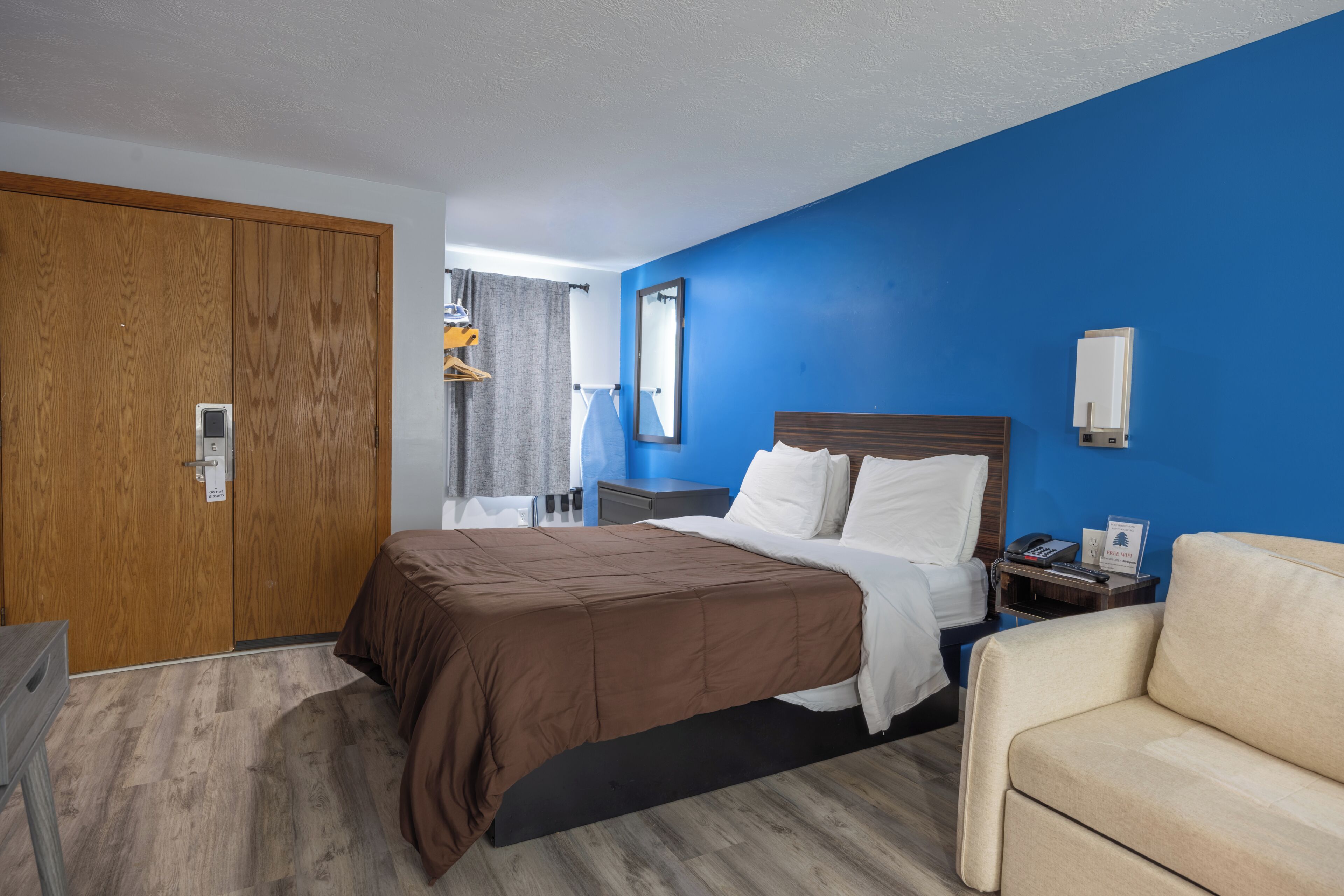 Habitación de hotel con cama, mesita de noche, silla, armario y espejo.