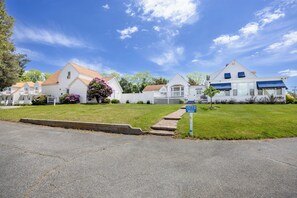 A residential street with white houses, a driveway, and a sign indicating an office. - Blue Spruce Motel & Townhouses (Plymouth)