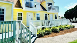 Un bâtiment jaune avec des balustrades blanches et des portes numérotées, probablement un hôtel ou un établissement proposant des hébergements.