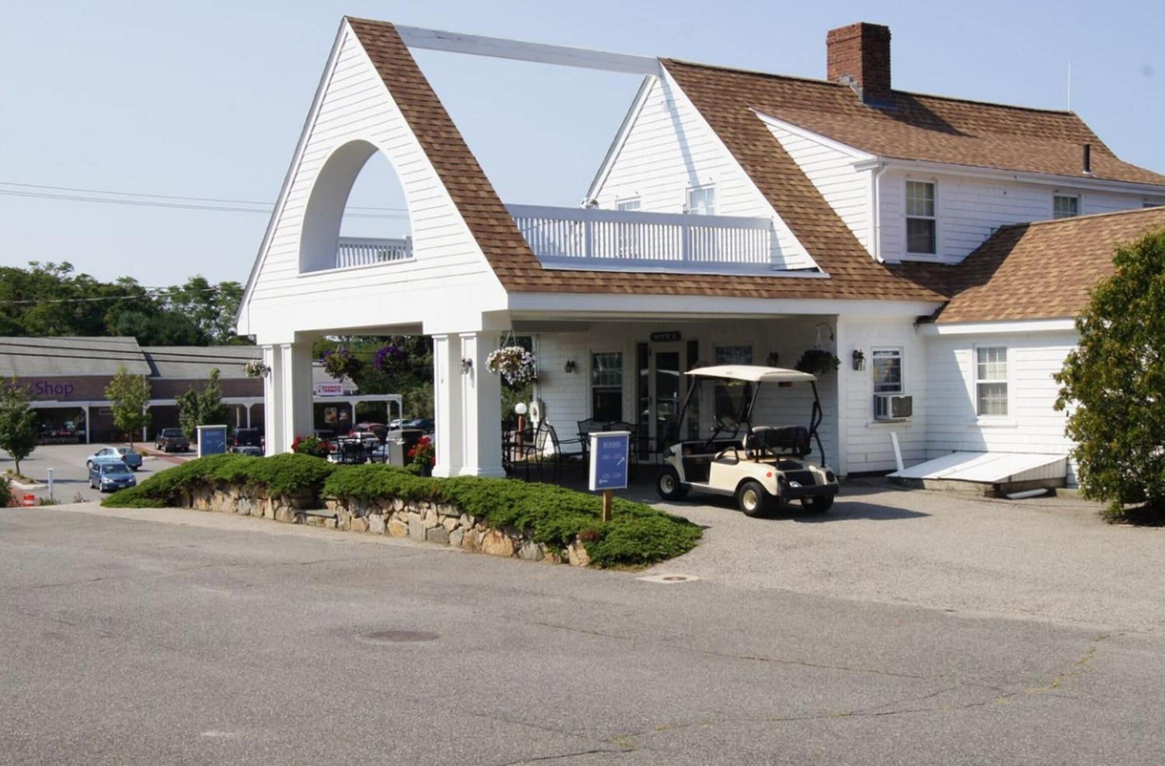 Un edificio blanco con un porche, un carrito de golf y un letrero que dice 'Shop'.