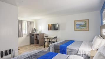 Quarto de hotel com duas camas, uma escrivaninha, uma televisão e um quadro na parede.
