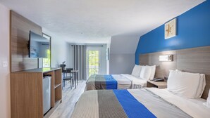 Une chambre d’hôtel avec deux lits, un bureau, un réfrigérateur et une grande fenêtre.