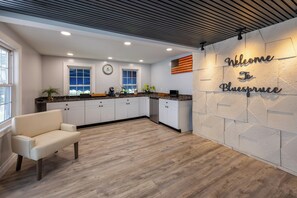 A modern kitchen with white cabinets, a wooden countertop, and a welcome sign.