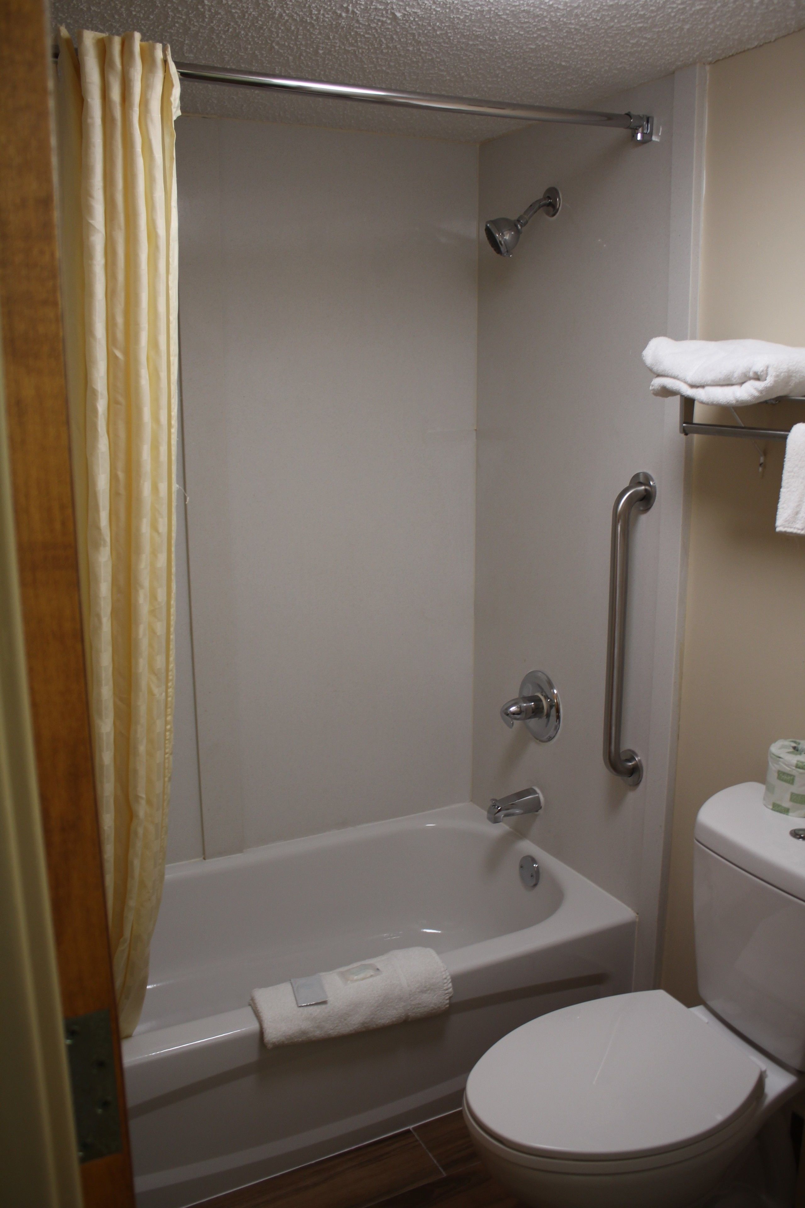 Une salle de bain équipée d’une baignoire, de toilettes et d’une douche avec une barre d’appui.
