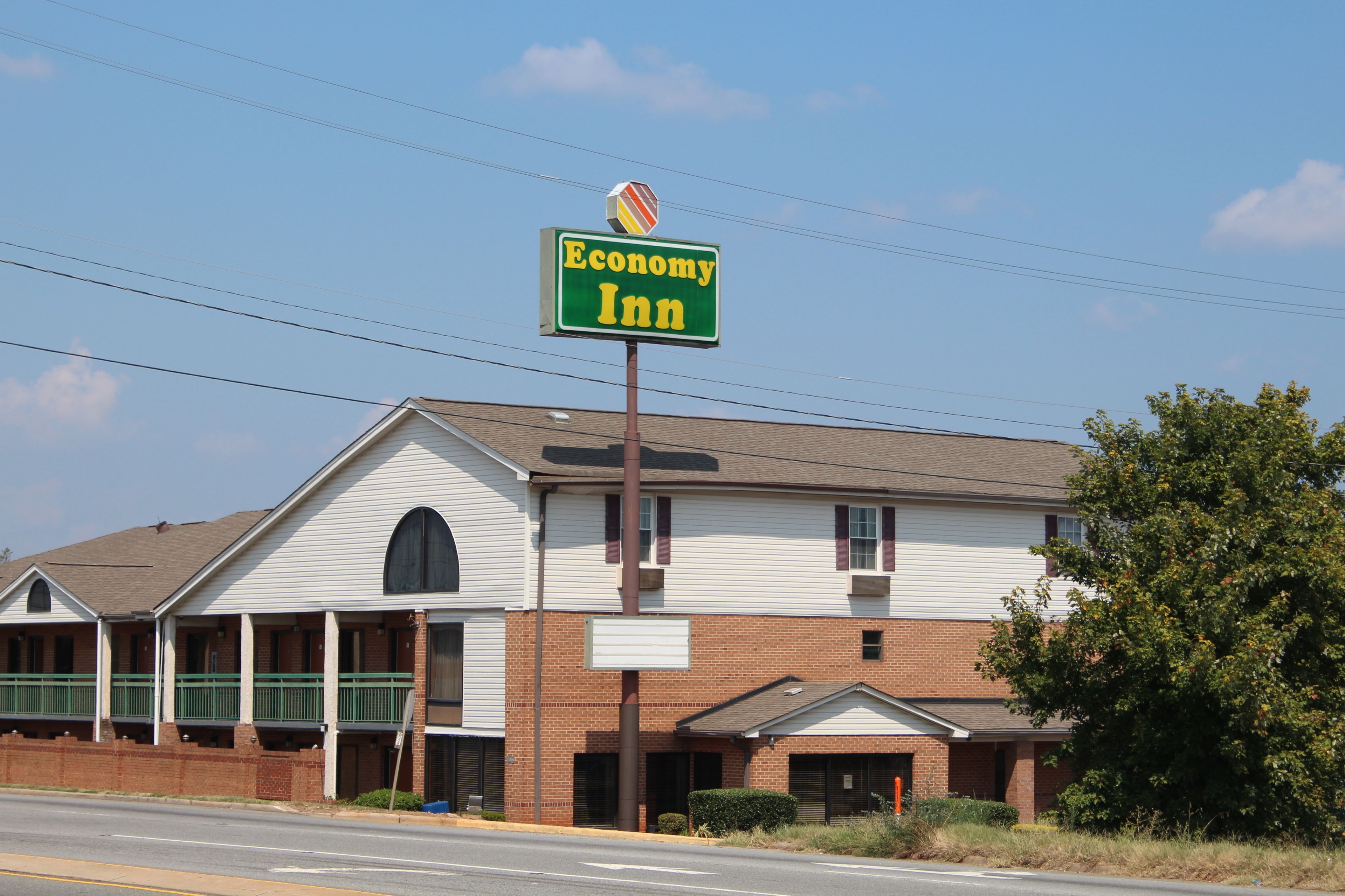A two-story Economy Inn with a green signboard, a brick facade, and a small attached garage.