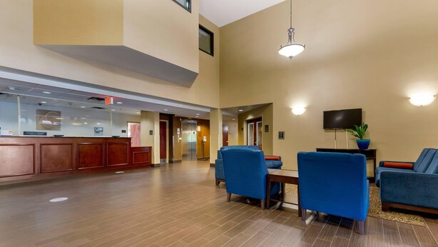 A spacious lobby with a reception desk, seating area, and a television screen.