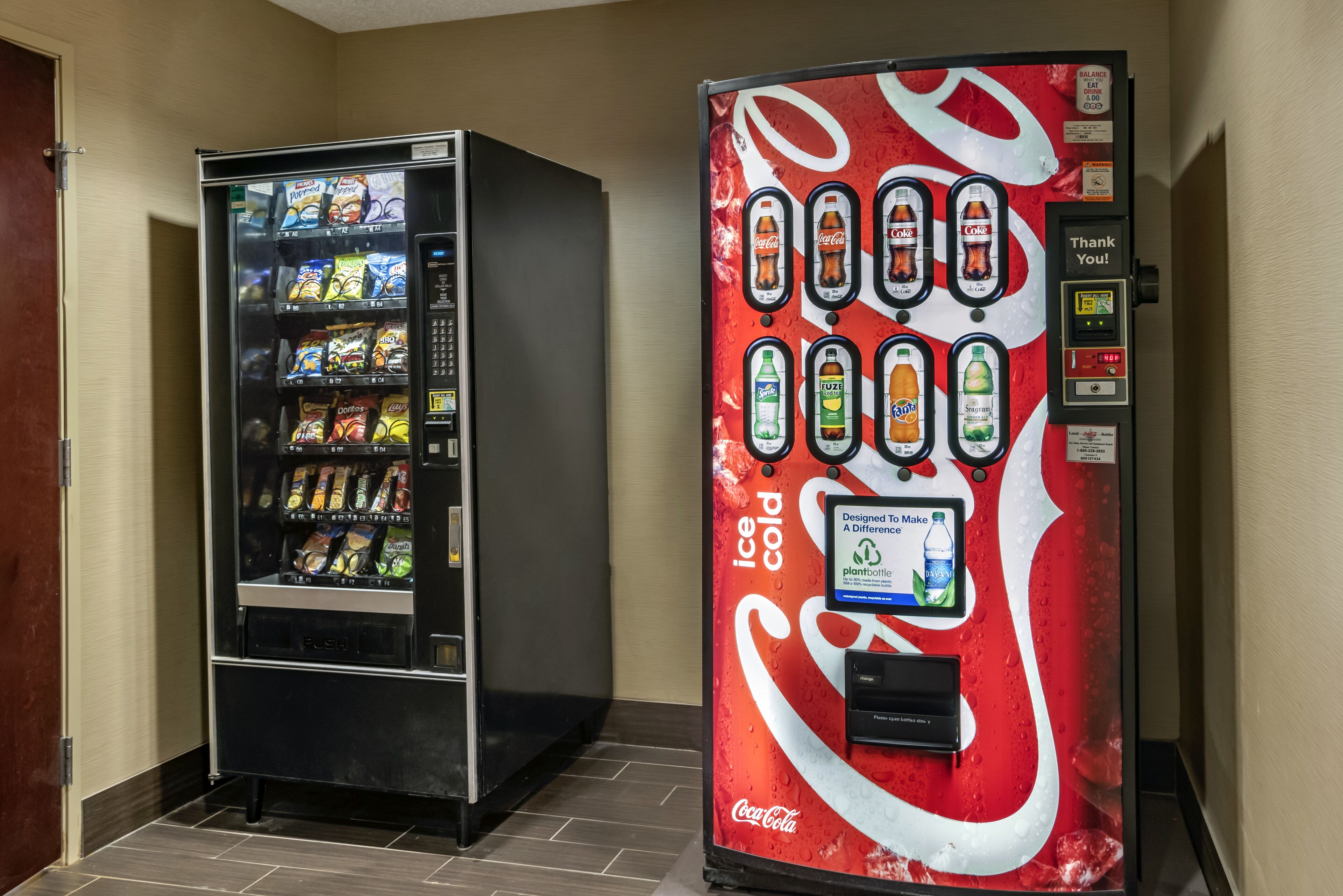 Two vending machines, one with snacks and the other with beverages, in a hallway.