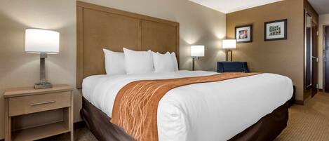 Ein Hotelzimmer mit einem großen Bett, zwei Nachttischen mit Lampen, einem Holz-Kopfteil und einem Teppichboden.