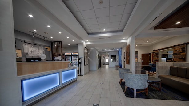 A modern hotel lobby with a reception desk, seating area, and a hallway leading to other rooms. - Holiday Inn Express & Suites Oklahoma City West-Yukon by IHG (Yukon)
