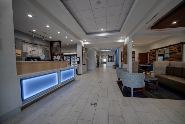 A modern hotel lobby with a reception desk, seating area, and a hallway leading to other rooms. - Holiday Inn Express & Suites Oklahoma City West-Yukon by IHG (Yukon)