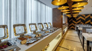 A buffet setup with multiple food stations, a seating area with tables and chairs, and a decorative ceiling with circular light fixtures. - Citrine Hotel (Bengaluru)