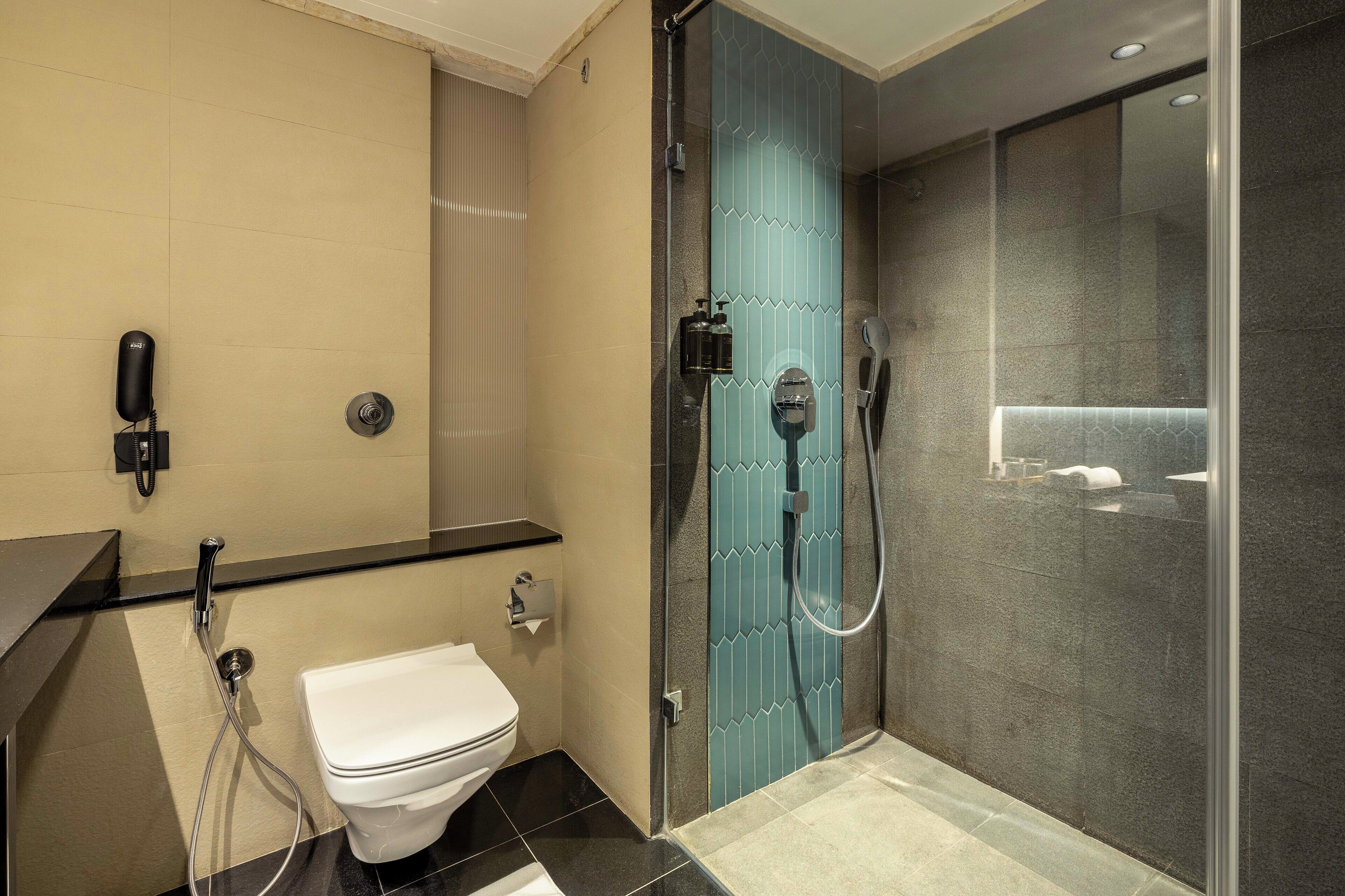Un baño moderno con inodoro, ducha con puerta de vidrio y lavamanos.