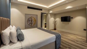 A modern bedroom with a large bed, a flat-screen TV mounted on the wall, and a wooden floor. - Citrine Hotel (Bengaluru)