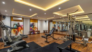 A modern gym with exercise equipment, wooden flooring, and a large mirror. - Citrine Hotel (Bengaluru)