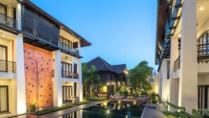 Un hotel moderno con piscina, balcones y un espacio exterior bien iluminado.