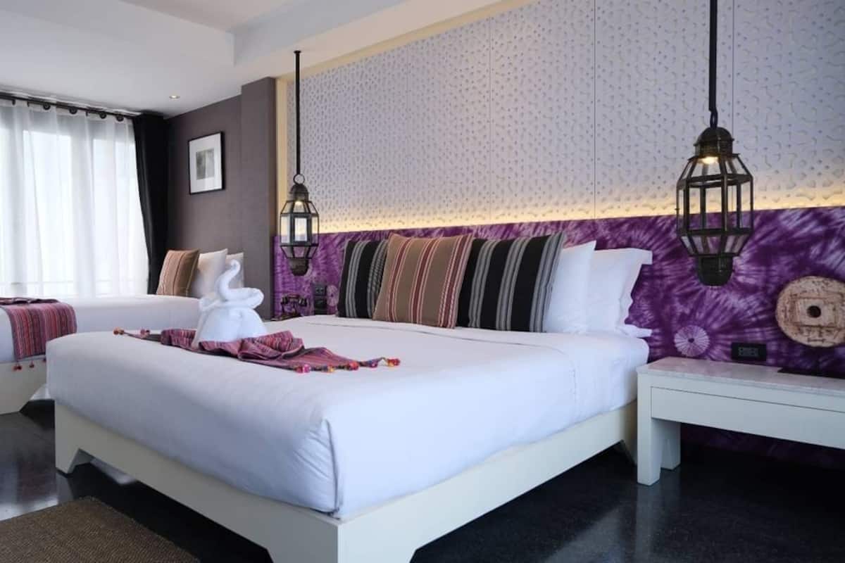A modern hotel room with a large bed, two bedside tables, a nightstand, and a decorative wall.