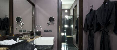 Un baño moderno con un espejo grande, un lavabo y una zona de ducha.