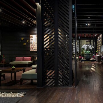 A modern interior with a wooden floor, a seating area with a sofa and chairs, and a decorative plant.