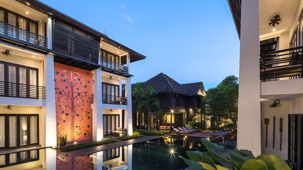 Un hotel moderno con piscina, varios balcones y un espacio exterior bien iluminado.