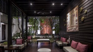 Un espacio interior acogedor con un banco de madera, asientos acolchados y una pared decorada con adornos colgantes.