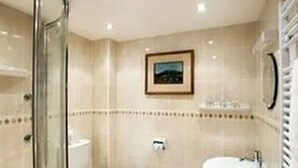 A bathroom with a glass shower enclosure, two sinks, and a framed picture on the wall. - Manston Guest House (Sturminster Newton)