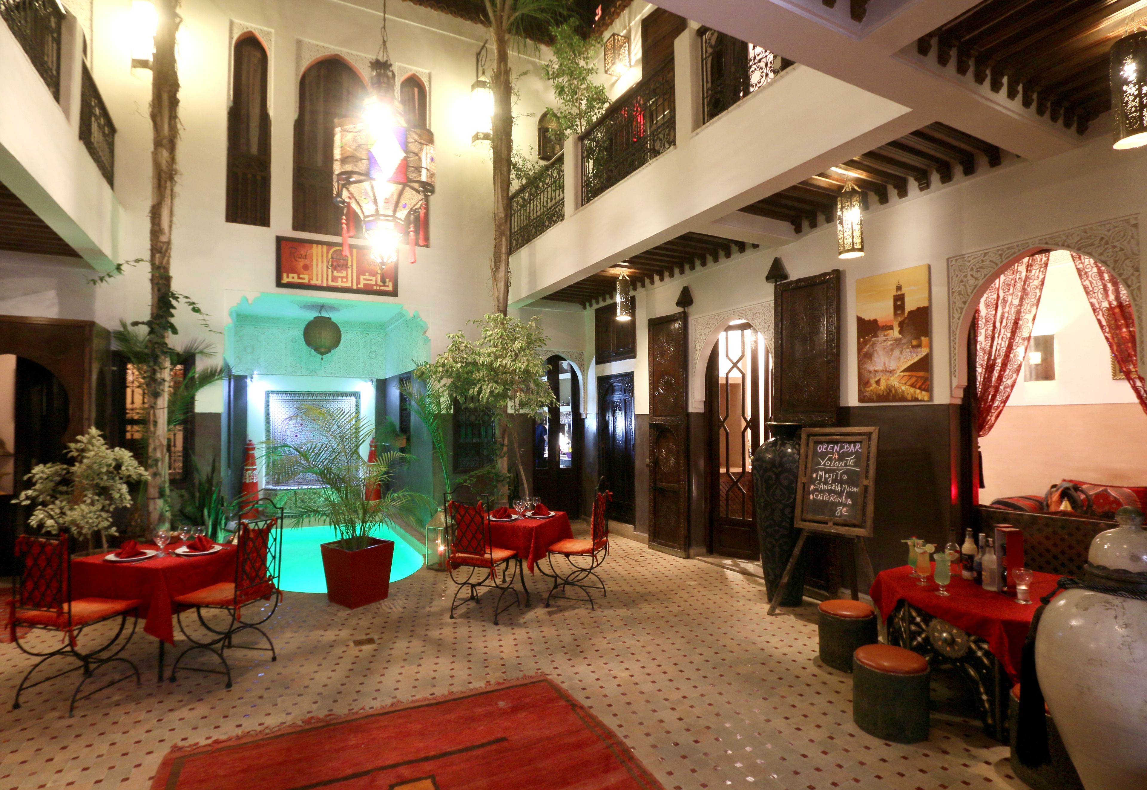 Un comedor con mesas y sillas, una planta colgante y un letrero que indica bar abierto.