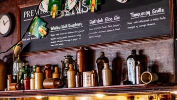 A bar menu with drink options and a shelf with various bottles and containers.