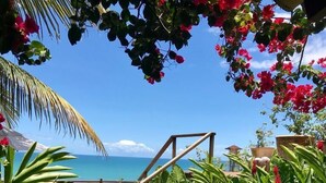 A garden with a wooden staircase leading to a deck overlooking the ocean. - Maitei Hotel (Porto Seguro)
