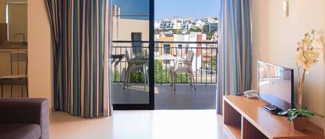 Une chambre d’hôtel moderne dotée d’un balcon, d’un canapé, d’une télévision et d’un coin repas.
