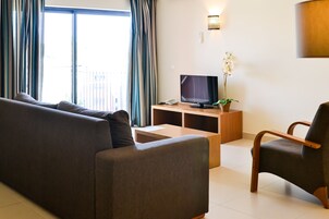 Una sala de estar con un sofá, un televisor, una mesita auxiliar y una silla.
