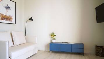 Een minimalistische woonkamer met een witte bank, een blauwe kast en een vloerlamp.