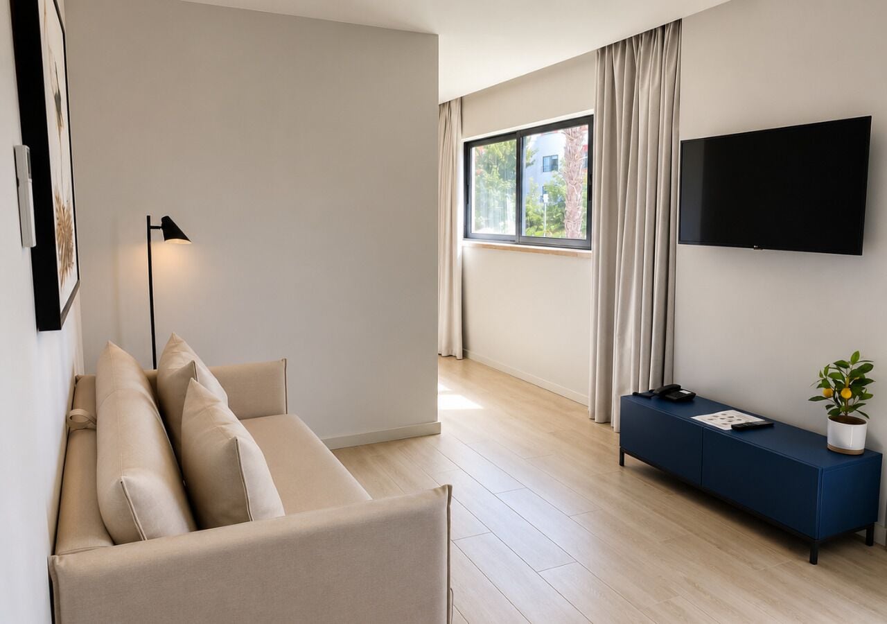Ein modernes Wohnzimmer mit einer Couch, einem blauen Konsolentisch, einem Flachbildfernseher und einem Fenster mit Vorhängen.