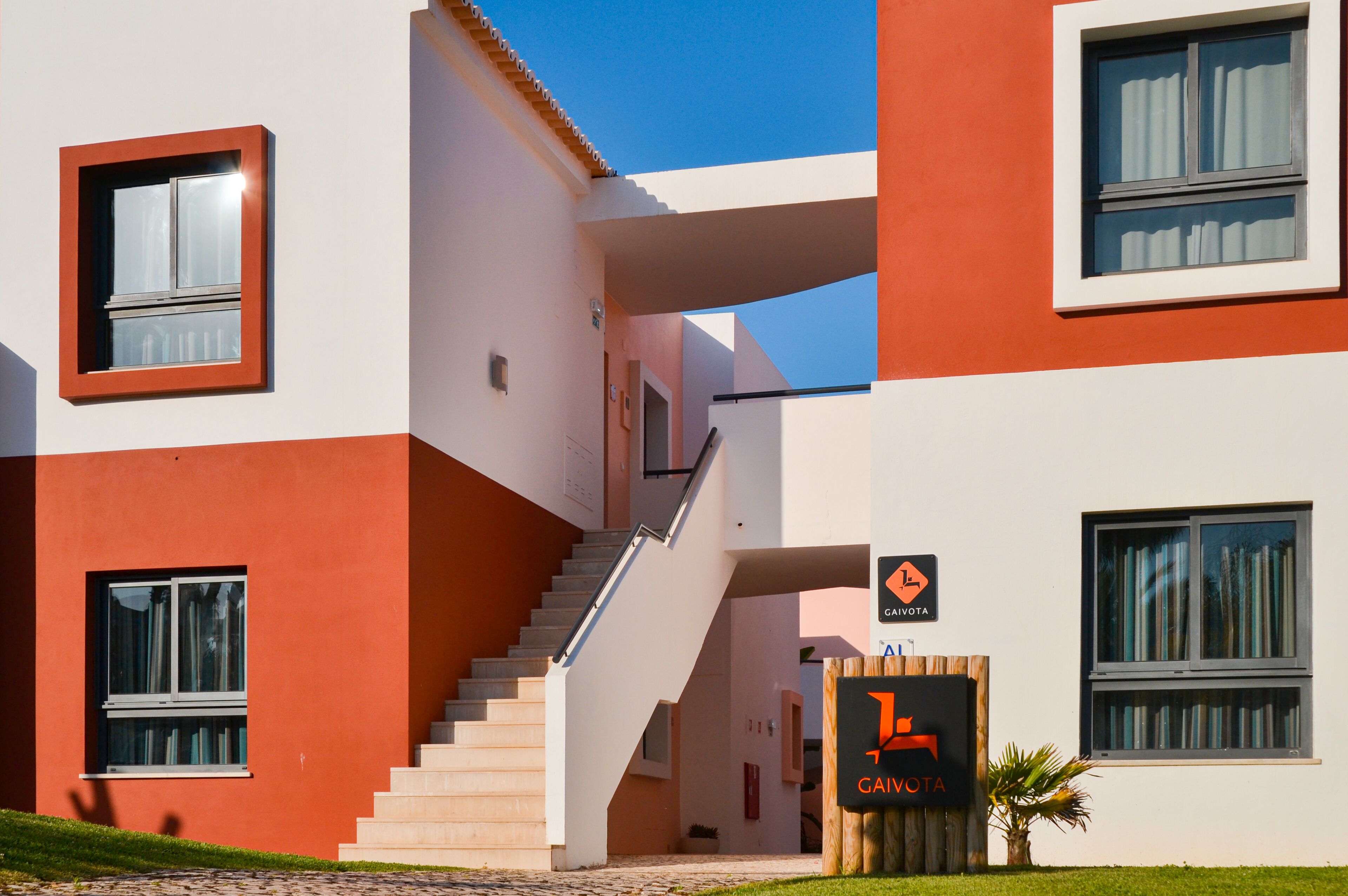 A modern building with a staircase leading to an upper level, a sign indicating 'GAVOTTA', and a clear sky.