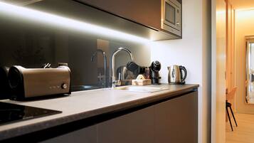 A modern kitchen with a built-in stove, a coffee maker, and a kettle on the counter.
