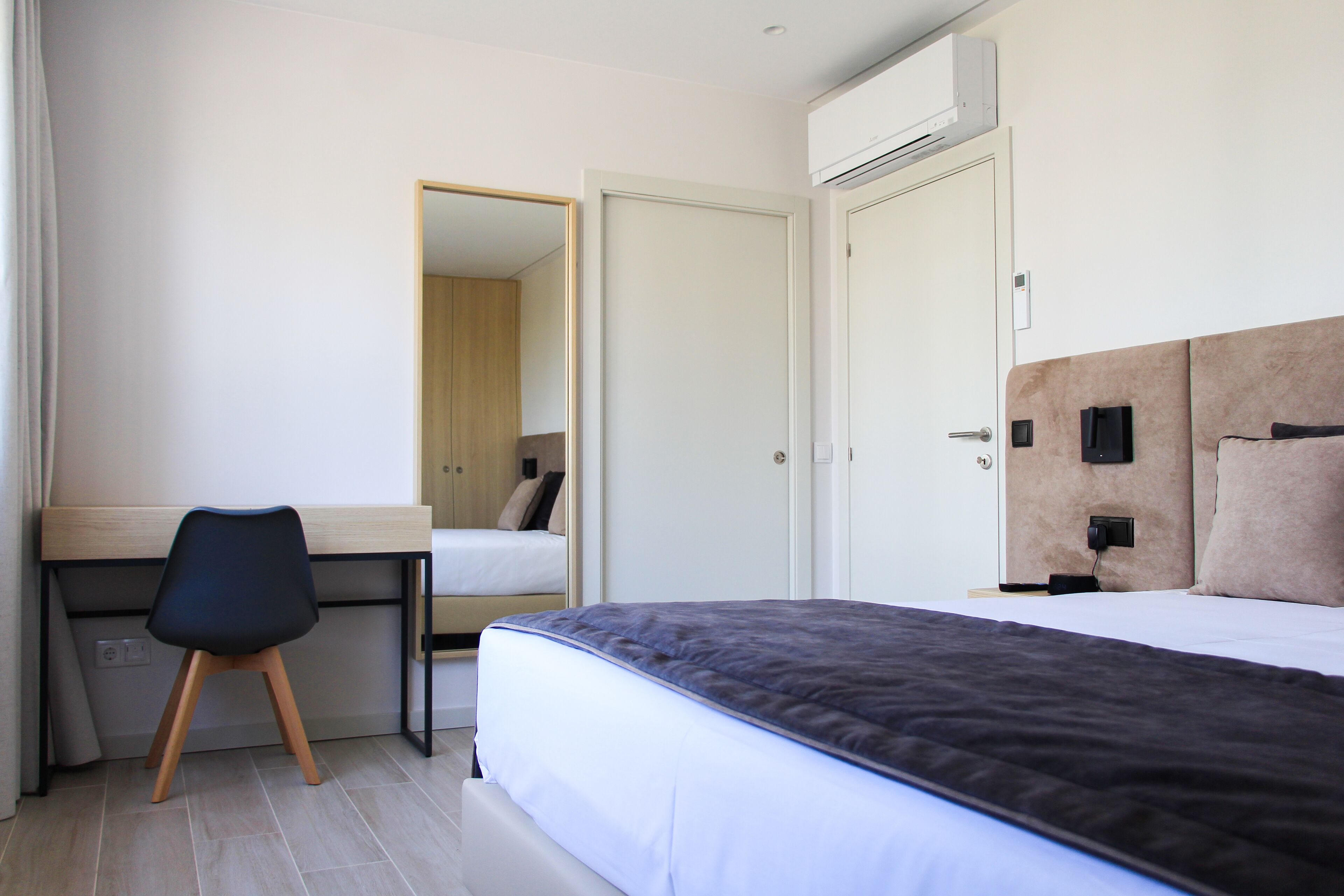 A bedroom with a bed, a desk, and a chair.