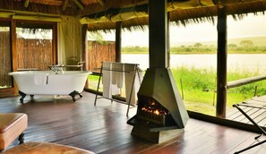 Habitació amb banyera, una llar de foc i vista a un camp de gespa.
