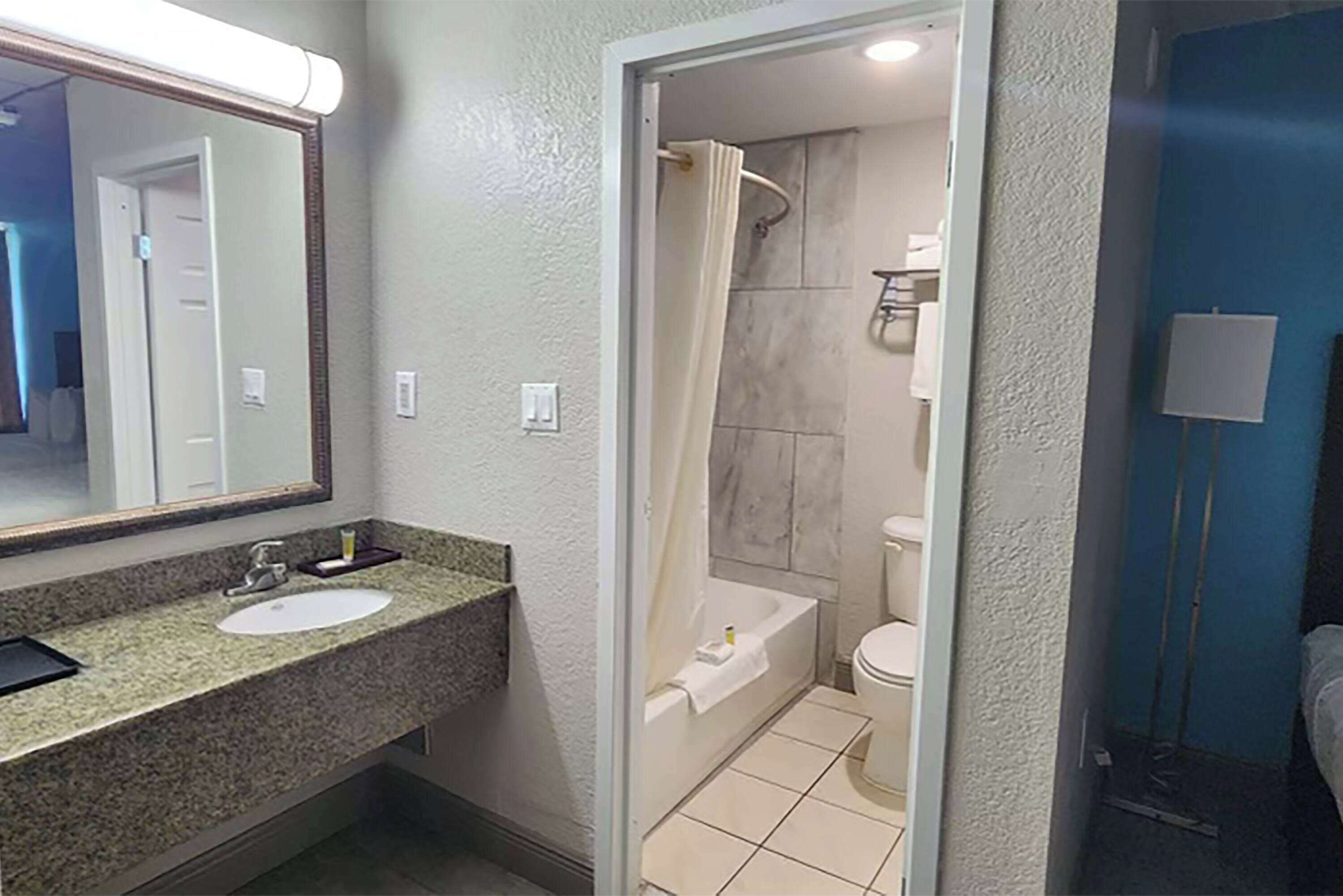 A bathroom with a sink, mirror, shower, and toilet.