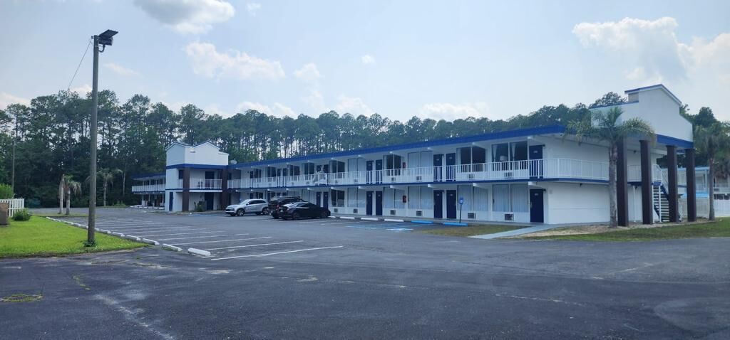 A motel with multiple rooms, a parking lot, and a small building with a balcony.
