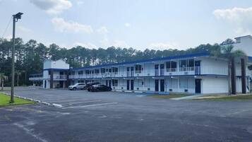 A motel with multiple rooms, a parking lot, and a small building with a balcony.