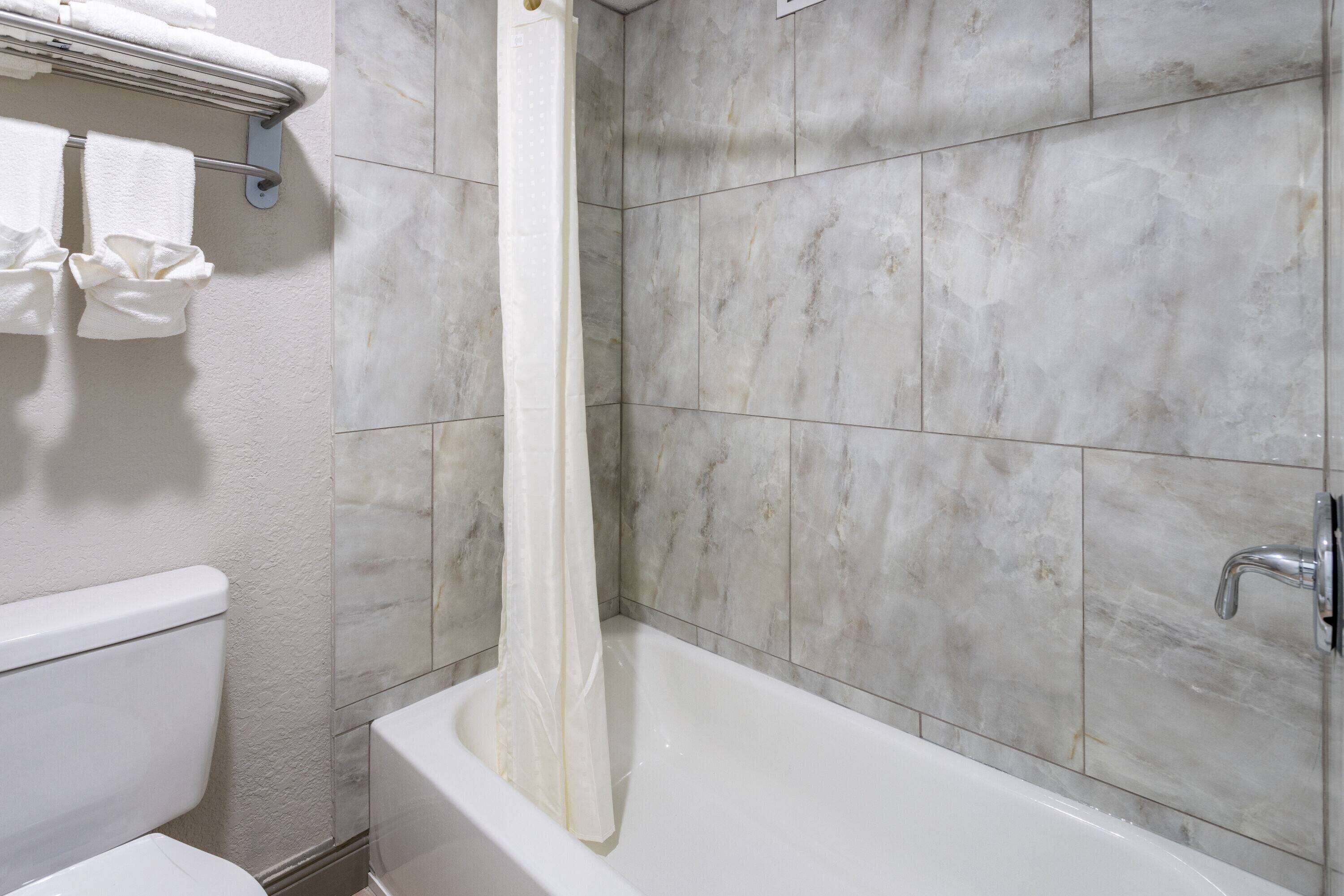 Un baño con bañera, cortina de ducha y retrete.
