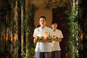 A person holding a tray with food items in a room with bamboo decorations. - Cherish Hotel (Hue)