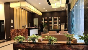 Eine moderne Lobby mit Empfangstresen, Sitzgelegenheiten und einem großen Fenster.