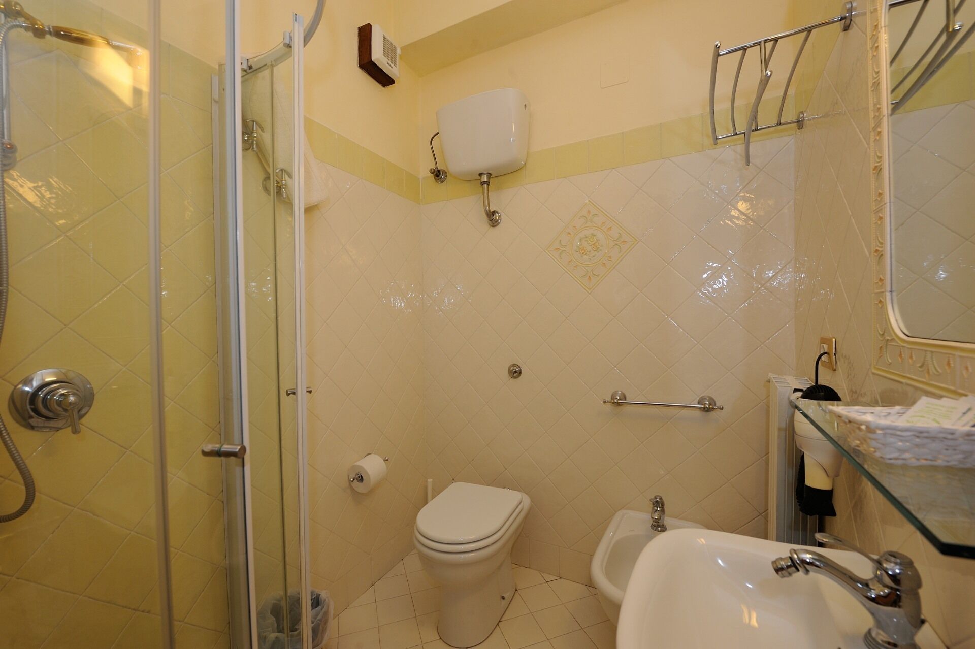 A bathroom with a glass shower enclosure, a toilet, a bidet, and a sink.