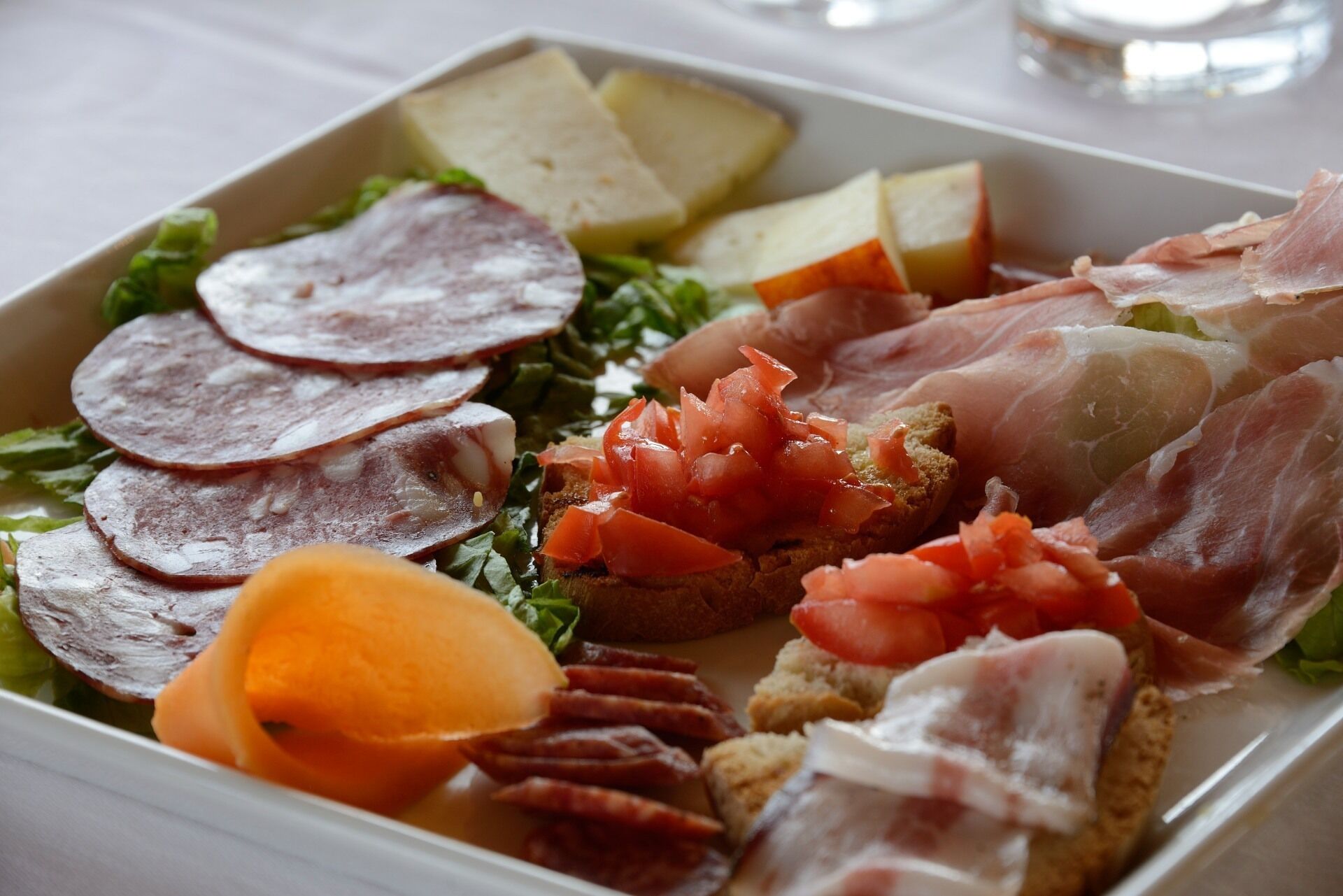 A platter of assorted meats and cheeses on a white plate.