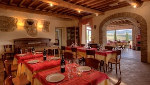 A restaurant with multiple tables set for dining, featuring a rustic wooden ceiling and stone walls. - Agrihotel Il Palagetto (Volterra)