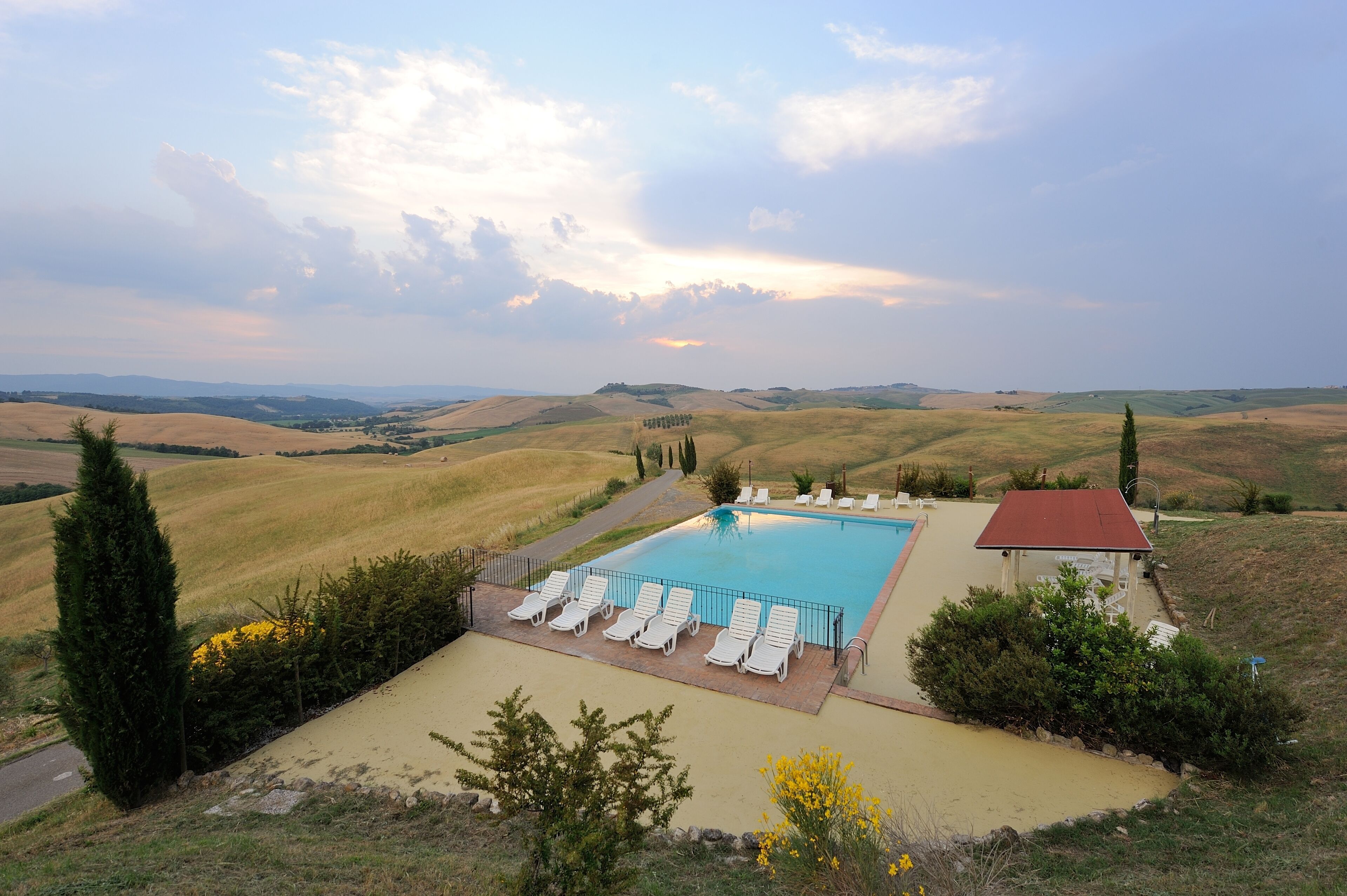 A rectangular swimming pool with lounge chairs, surrounded by a landscaped area with a view of rolling hills.