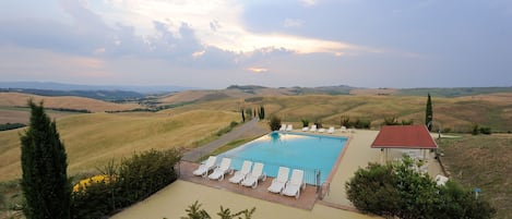 A rectangular swimming pool with lounge chairs, surrounded by a landscaped area with a view of rolling hills.