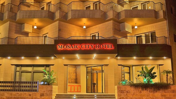A multi-story hotel with balconies, a staircase leading to the entrance, and a sign reading "MOSAIC CITY HOTEL". - Mosaic City Hotel (Madaba)