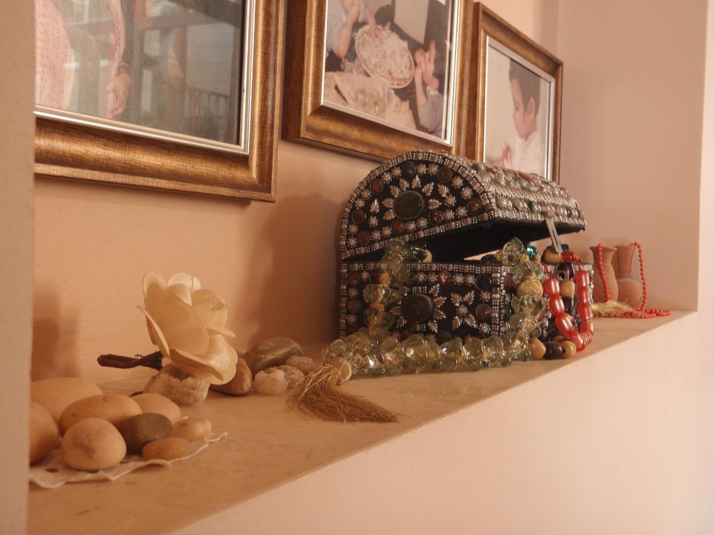 A shelf with decorative items including a beaded bag, a red beaded necklace, and a vase.